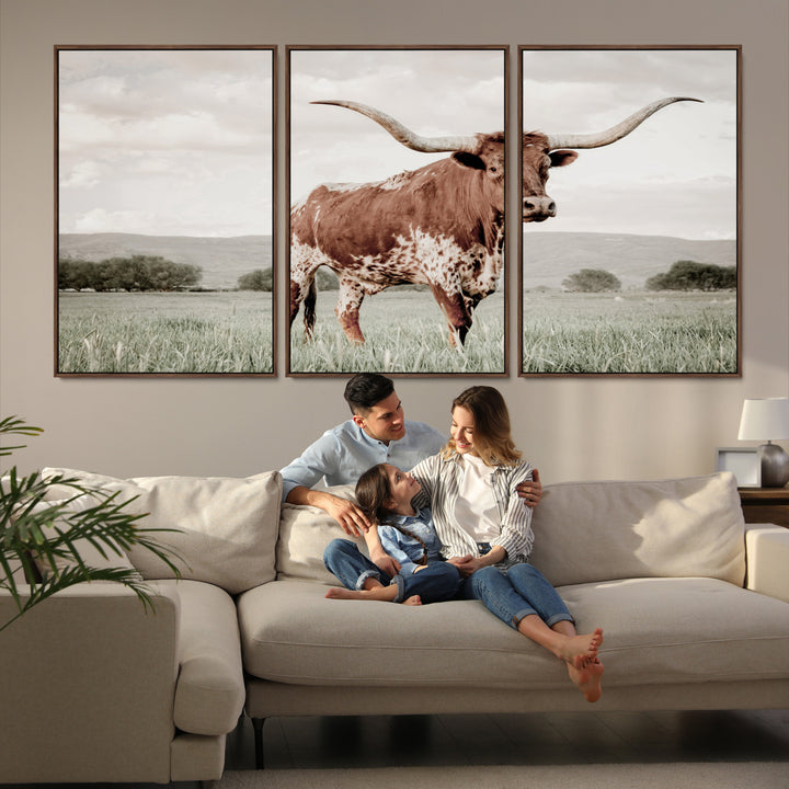 Canvas of a Texas longhorn standing in a grassy field with mountains in the background, ideal for rustic or country-style western wall decor.