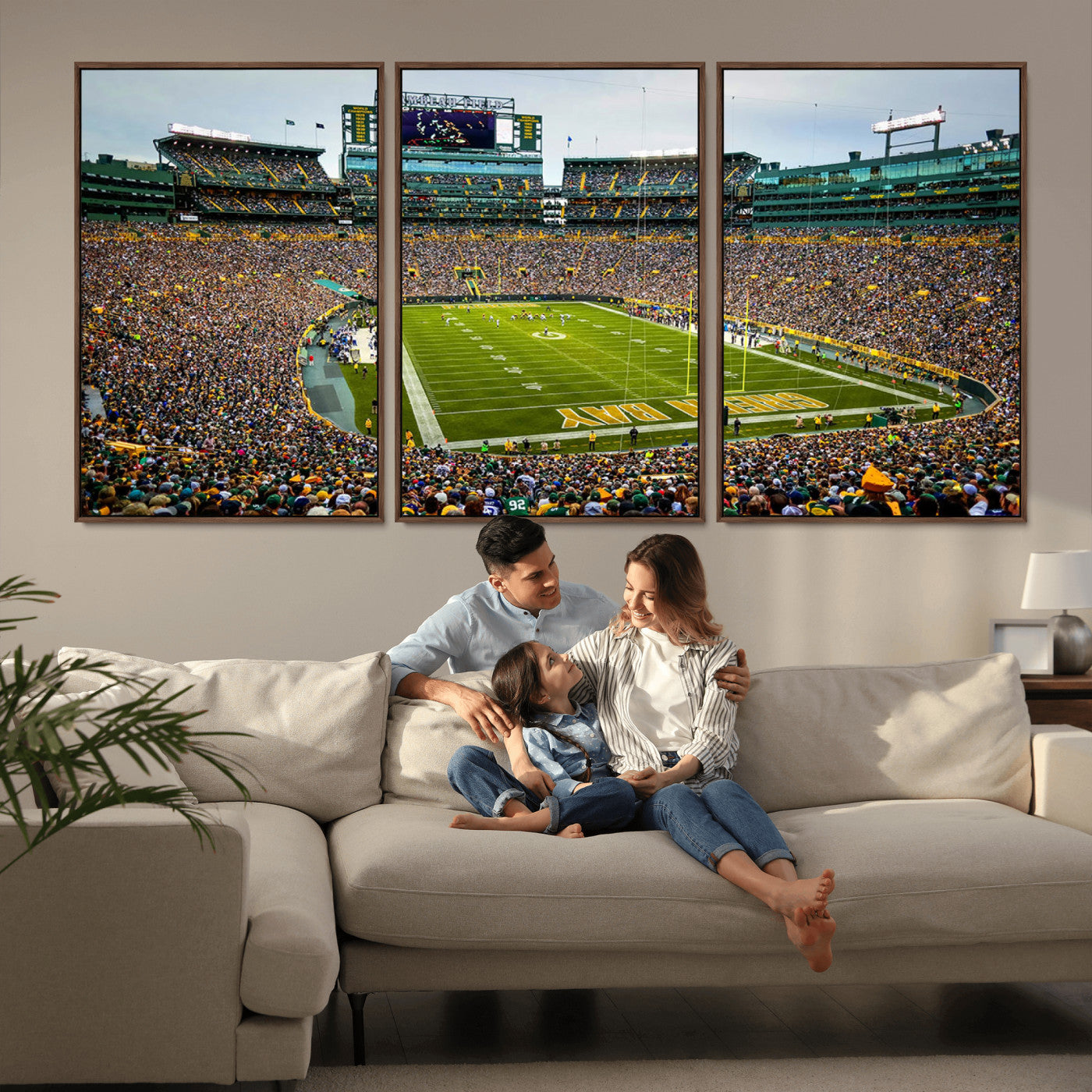 Packed football stadium with thousands of fans watching an American football game on a well-maintained field. The scoreboard displays "Lambeau Field," and players are lined up on the field. The stadium is surrounded by multiple tiers of seating filled wit