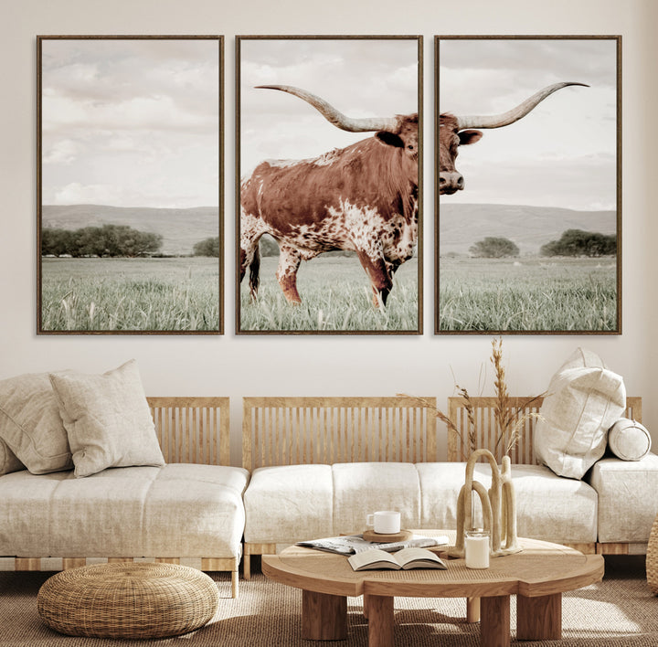 Canvas of a Texas longhorn standing in a grassy field with mountains in the background, ideal for rustic or country-style western wall decor.