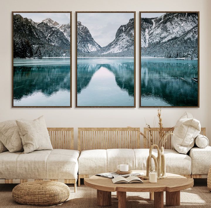 Crystal-clear alpine lake reflecting snow-covered mountains, surrounded by evergreen trees, creating a serene and tranquil winter landscape.
