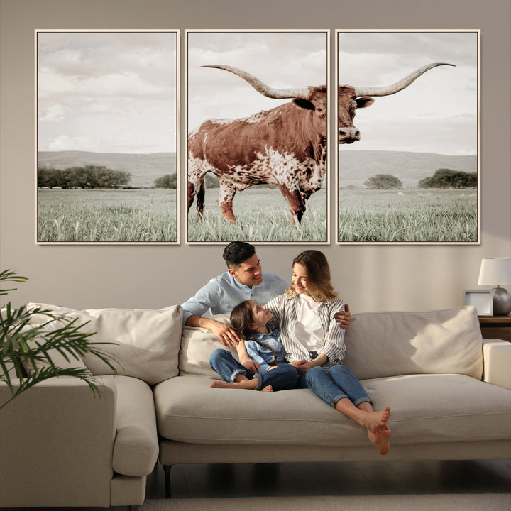 Canvas of a Texas longhorn standing in a grassy field with mountains in the background, ideal for rustic or country-style western wall decor.