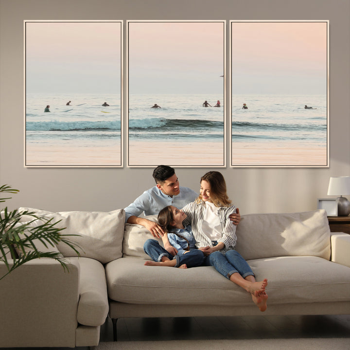 Dreamy photo of surfers waiting on soft pastel waves under a pink sunset sky, ideal for soft coastal minimalist or serene ocean-themed home decor.