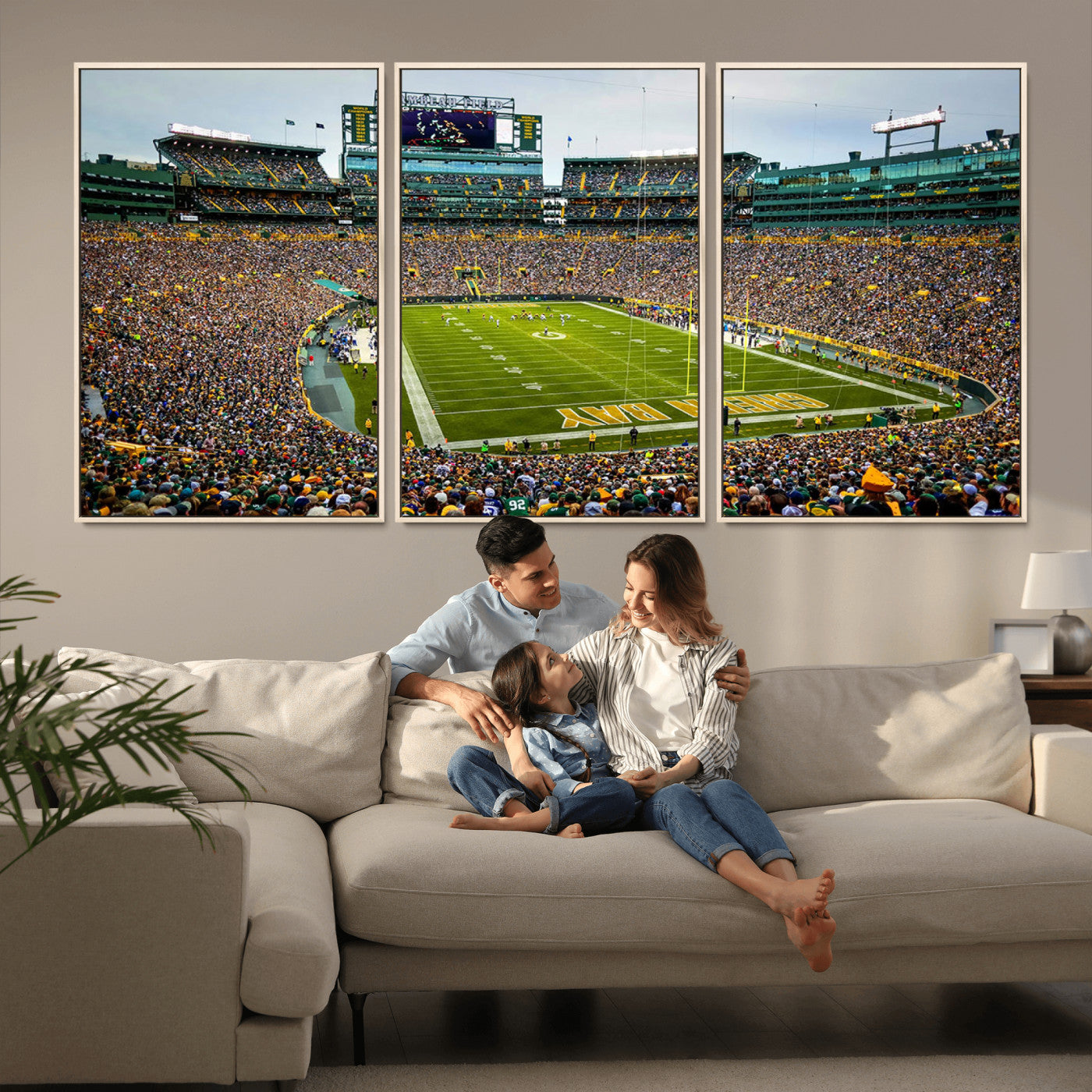 Packed football stadium with thousands of fans watching an American football game on a well-maintained field. The scoreboard displays "Lambeau Field," and players are lined up on the field. The stadium is surrounded by multiple tiers of seating filled wit