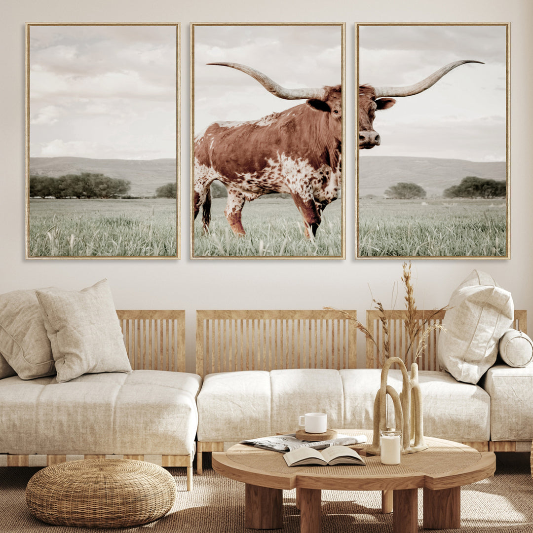 Canvas of a Texas longhorn standing in a grassy field with mountains in the background, ideal for rustic or country-style western wall decor.