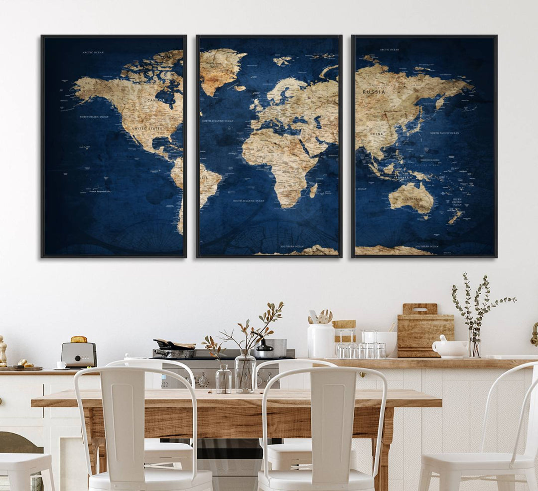 A large framed world map canvas print features beige landmasses set against a grunge-stained deep blue ocean background, creating an intriguing piece of wall art.