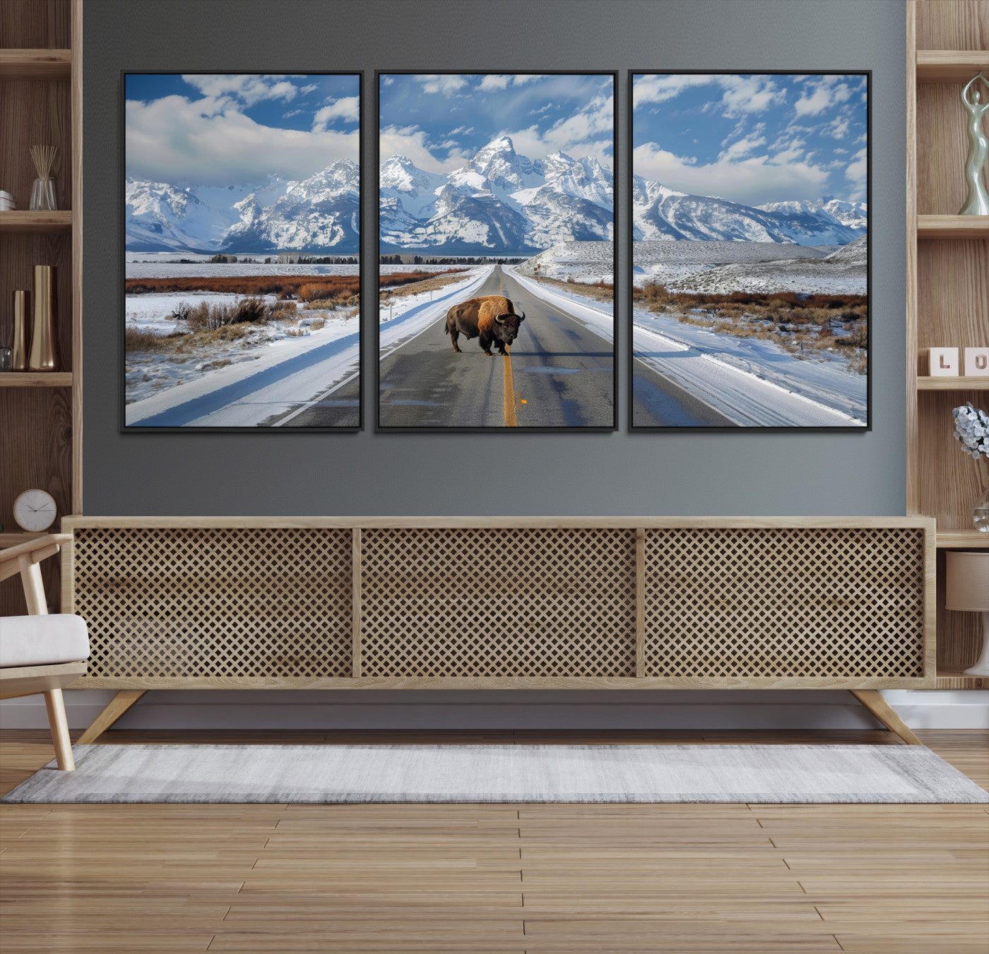 A powerful bison stands on a snow-dusted road beneath the towering peaks of the Grand Tetons, capturing the untamed beauty of America's winter wilderness.