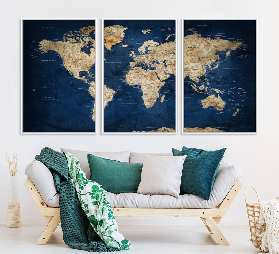 A large framed world map canvas print features beige landmasses set against a grunge-stained deep blue ocean background, creating an intriguing piece of wall art.