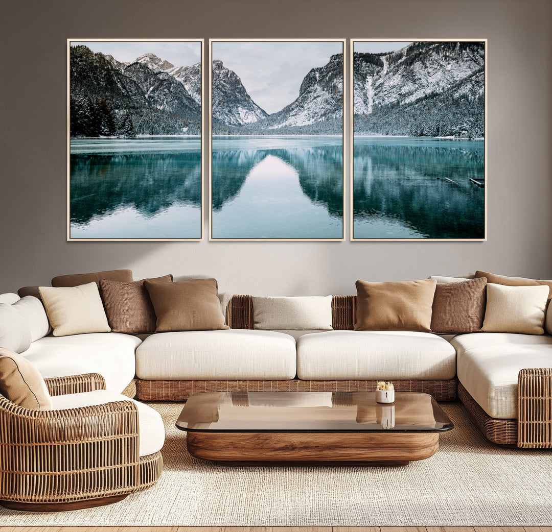 Crystal-clear alpine lake reflecting snow-covered mountains, surrounded by evergreen trees, creating a serene and tranquil winter landscape.