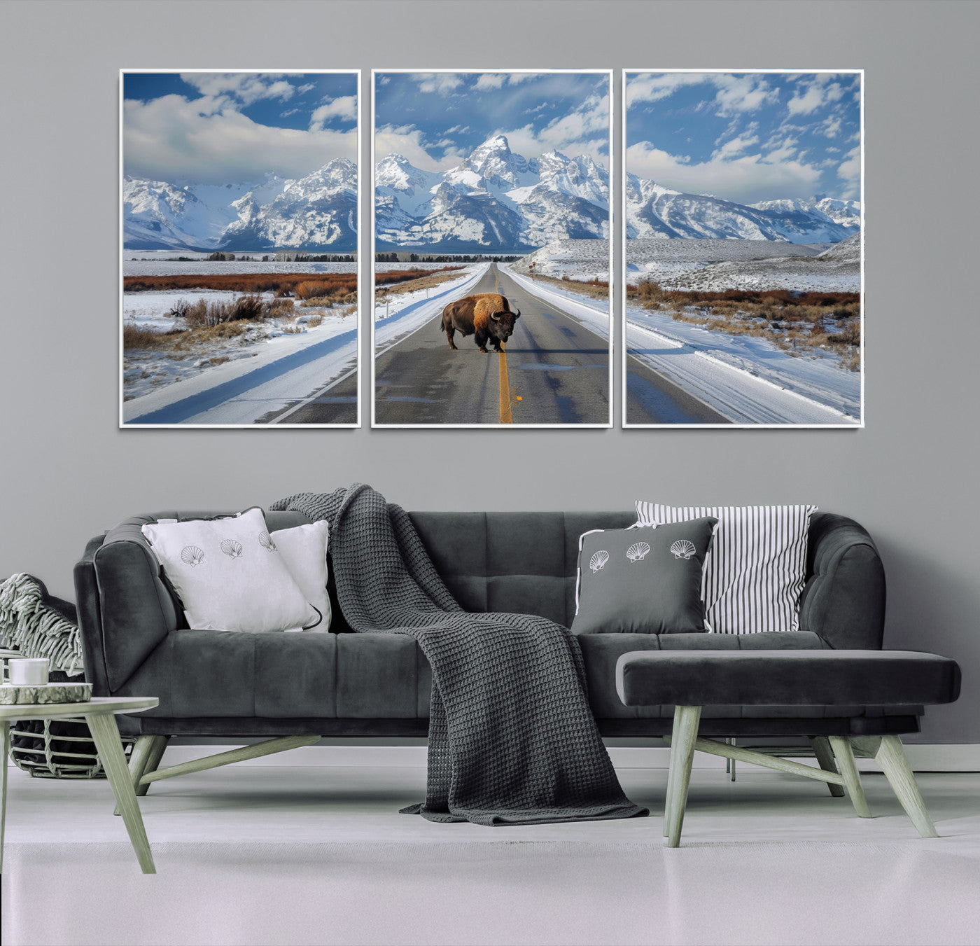 A powerful bison stands on a snow-dusted road beneath the towering peaks of the Grand Tetons, capturing the untamed beauty of America's winter wilderness.