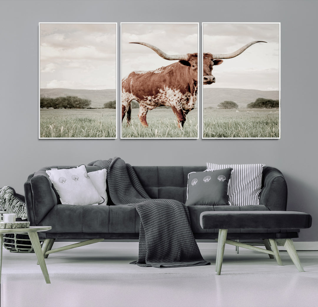 Canvas of a Texas longhorn standing in a grassy field with mountains in the background, ideal for rustic or country-style western wall decor.