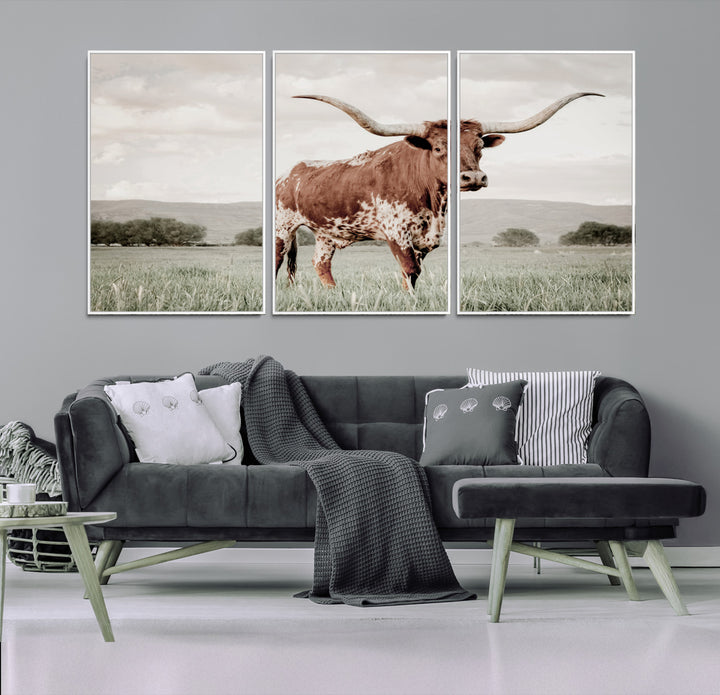 Canvas of a Texas longhorn standing in a grassy field with mountains in the background, ideal for rustic or country-style western wall decor.
