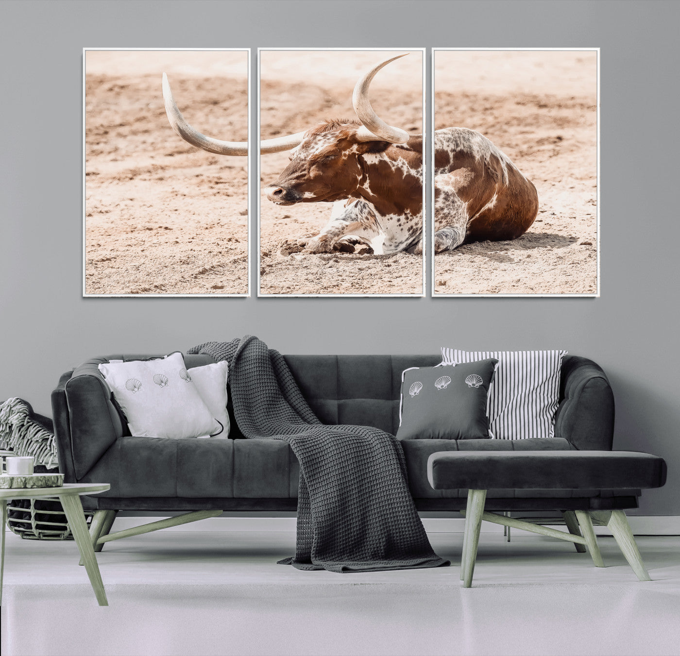 Texas Longhorn bull resting on dusty ground with warm tones, ideal for rustic western or farmhouse-themed wall decor.