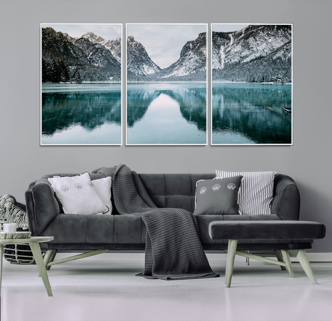 Crystal-clear alpine lake reflecting snow-covered mountains, surrounded by evergreen trees, creating a serene and tranquil winter landscape.