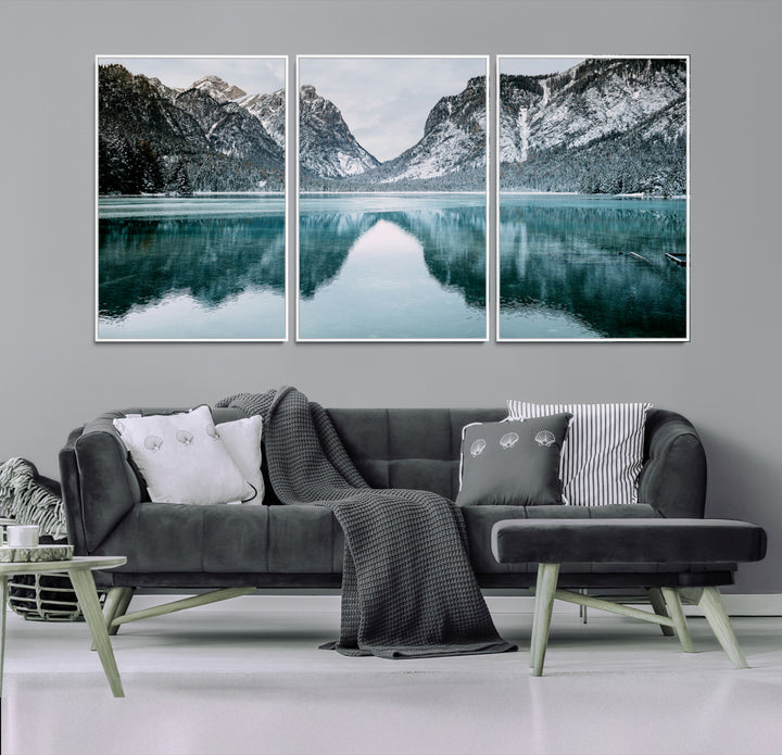 Crystal-clear alpine lake reflecting snow-covered mountains, surrounded by evergreen trees, creating a serene and tranquil winter landscape.