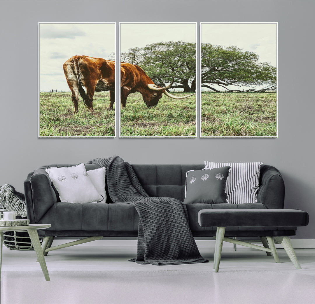 A Texas Longhorn grazing in a green pasture with a large tree in the background, evoking a rustic Western and farmhouse aesthetic.