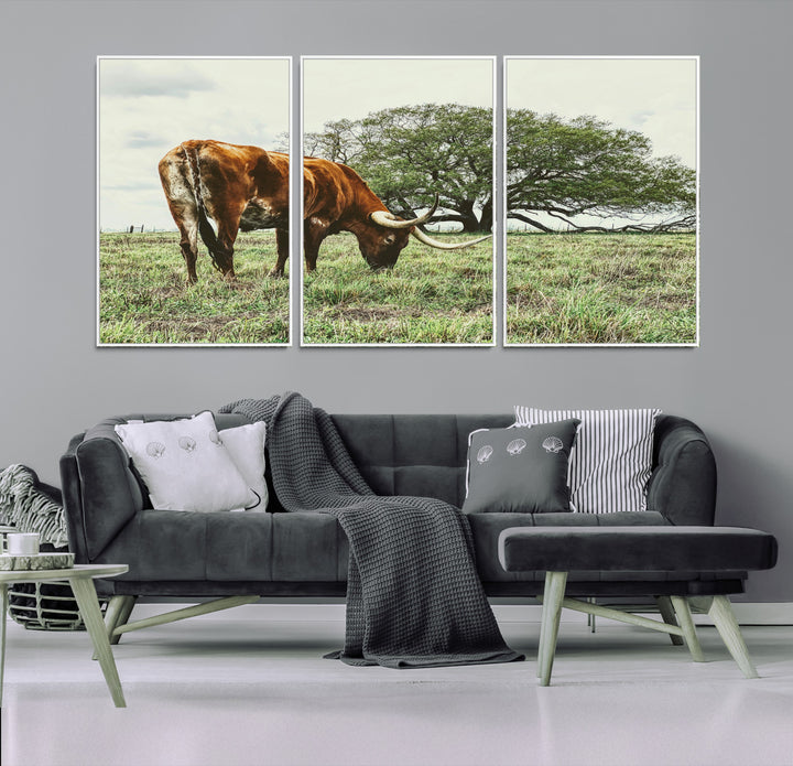 A Texas Longhorn grazing in a green pasture with a large tree in the background, evoking a rustic Western and farmhouse aesthetic.