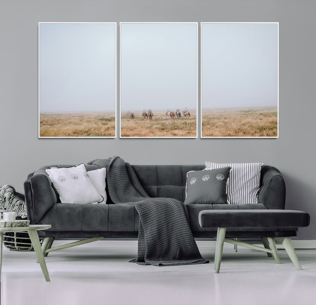 A group of horseback riders moving through a fog-shrouded field, evoking a calm Western scene with golden grasses and soft horizons.
