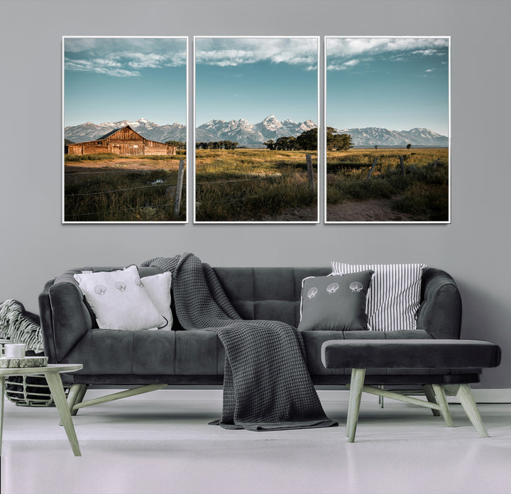 A rustic farmhouse with a wooden barn set against majestic mountain peaks under a soft blue sky, evoking peaceful countryside charm.