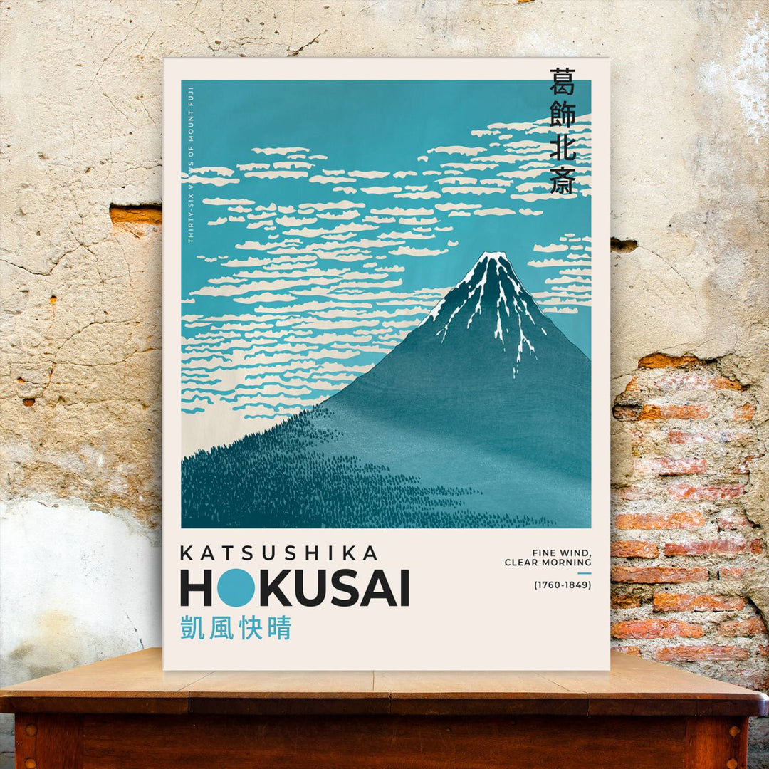 The Katsushika Hokusai Fine Wind, Clear Morning Canvas Wall Art Print, showcasing Mount Fuji with clouds, is displayed against a textured wall. This iconic Japanese art piece offers a premium canvas and gallery-quality finish that enhances any space as stunning wall decor.