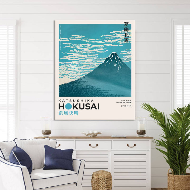 The Katsushika Hokusai Fine Wind, Clear Morning Canvas Wall Art Print, showcasing Mount Fuji with clouds, is displayed against a textured wall. This iconic Japanese art piece offers a premium canvas and gallery-quality finish that enhances any space as stunning wall decor.