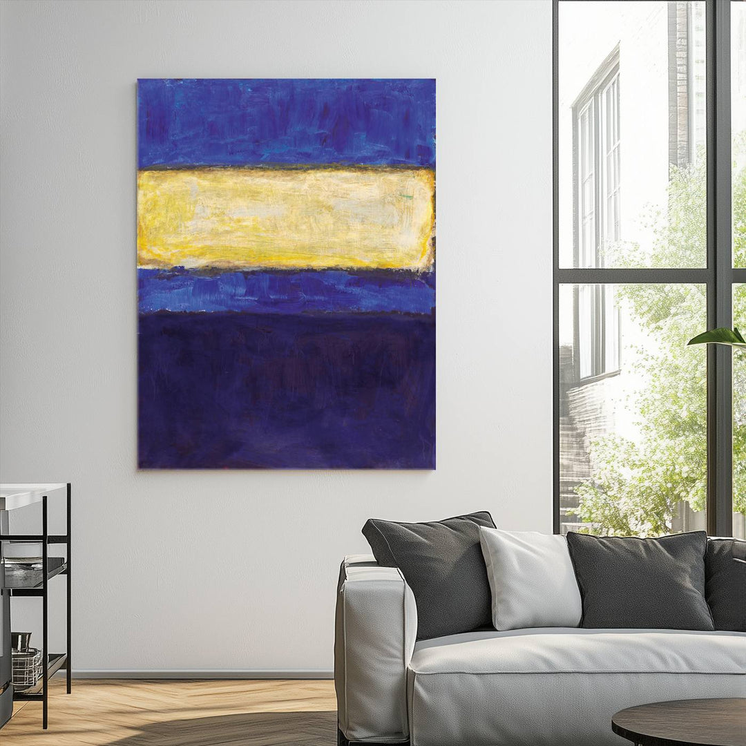 A Mark Rothko set of canvas wall art print, featuring a reproduction of abstract color art with blue, yellow, and purple hues, hangs on a white wall in a modern, sunlit room.