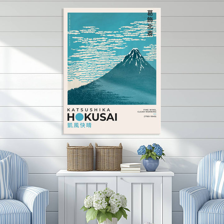 The Katsushika Hokusai Fine Wind, Clear Morning Canvas Wall Art Print, showcasing Mount Fuji with clouds, is displayed against a textured wall. This iconic Japanese art piece offers a premium canvas and gallery-quality finish that enhances any space as stunning wall decor.