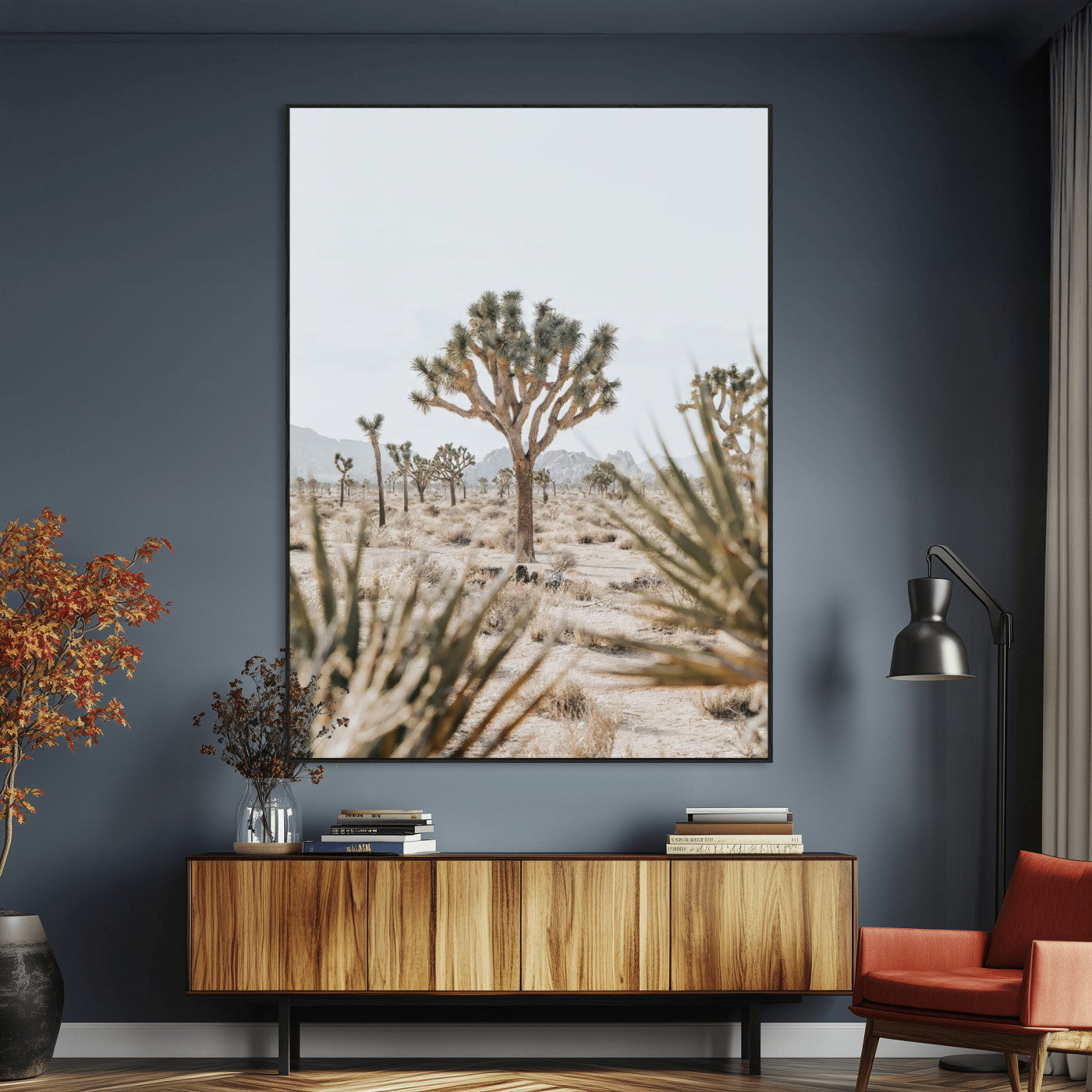 A wide desert landscape featuring multiple Joshua trees with spiky leaves and twisted branches, set against a pale sky and distant rocky hills. The foreground has blurred desert shrubs, emphasizing depth.