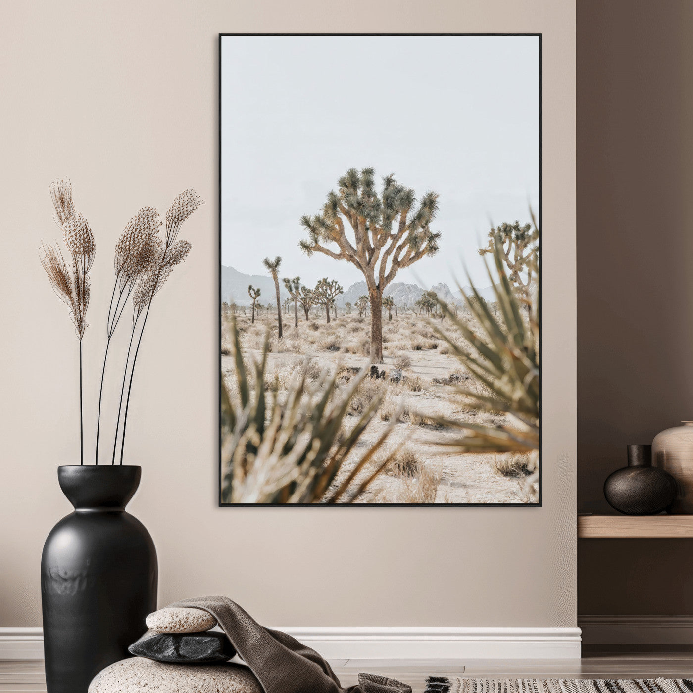 A wide desert landscape featuring multiple Joshua trees with spiky leaves and twisted branches, set against a pale sky and distant rocky hills. The foreground has blurred desert shrubs, emphasizing depth.