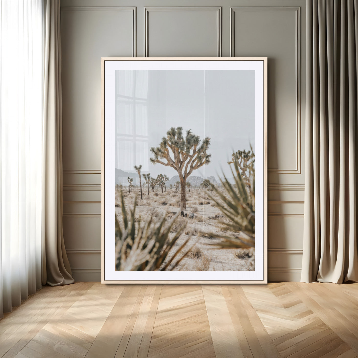 A wide desert landscape featuring multiple Joshua trees with spiky leaves and twisted branches, set against a pale sky and distant rocky hills. The foreground has blurred desert shrubs, emphasizing depth.