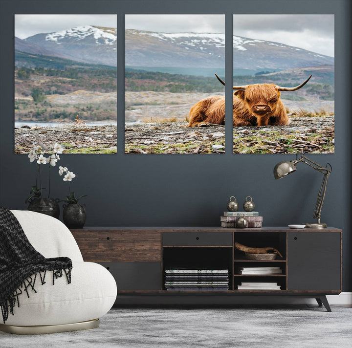 Highland Cow Horn Farm Wall Art Canvas Print is displayed against a wooden wall featuring a mountainous backdrop.