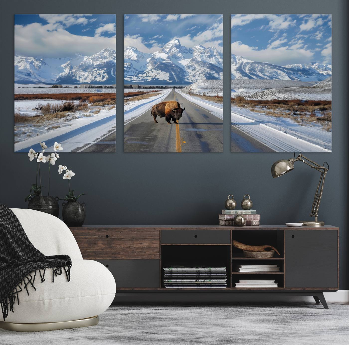 A powerful bison stands on a snow-dusted road beneath the towering peaks of the Grand Tetons, capturing the untamed beauty of America's winter wilderness.