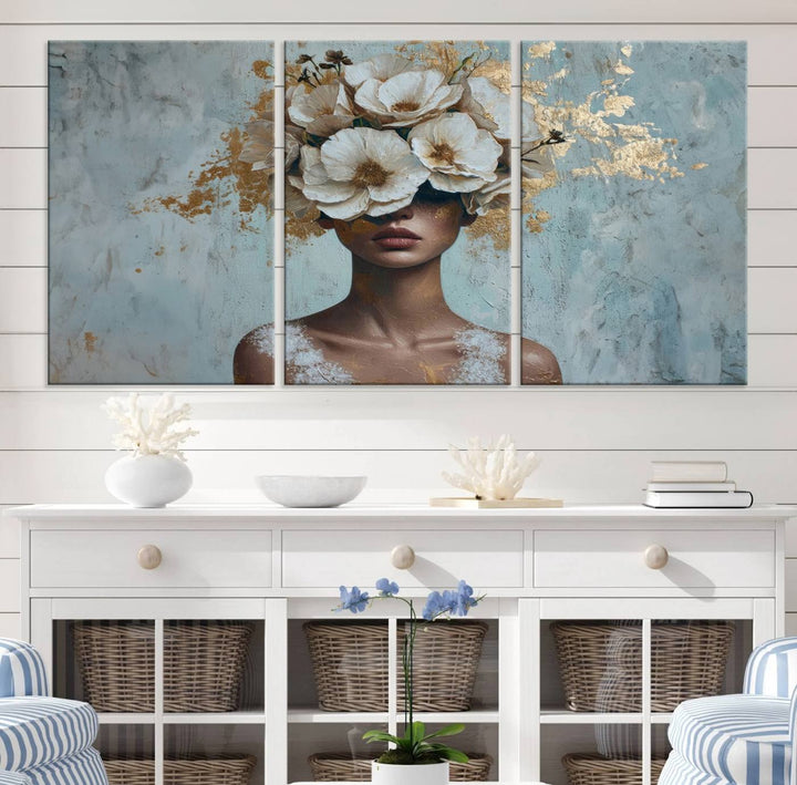 The Golden Petal Silhouette Woman Wall Art Canvas Print, a large 3-panel canvas with a textured gold floral design, serves as a luxurious centerpiece in modern glam settings. The artwork depicts a woman with flowers over her eyes against a textured background and hangs elegantly.