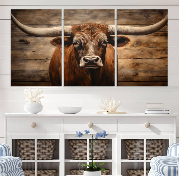 The Longhorn Bull Wall Art, a ready-to-hang canvas print, showcases an image of a brown longhorn cow set against a wooden background, perfect for those looking to enhance their space with rustic farmhouse and western barn decor.