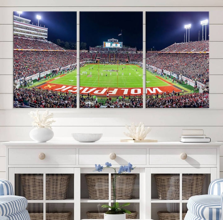 A NC State Wolfpack Football Team print of Carter-Finley Stadium at night features WOLFPACK illuminated brightly in the end zone grass.