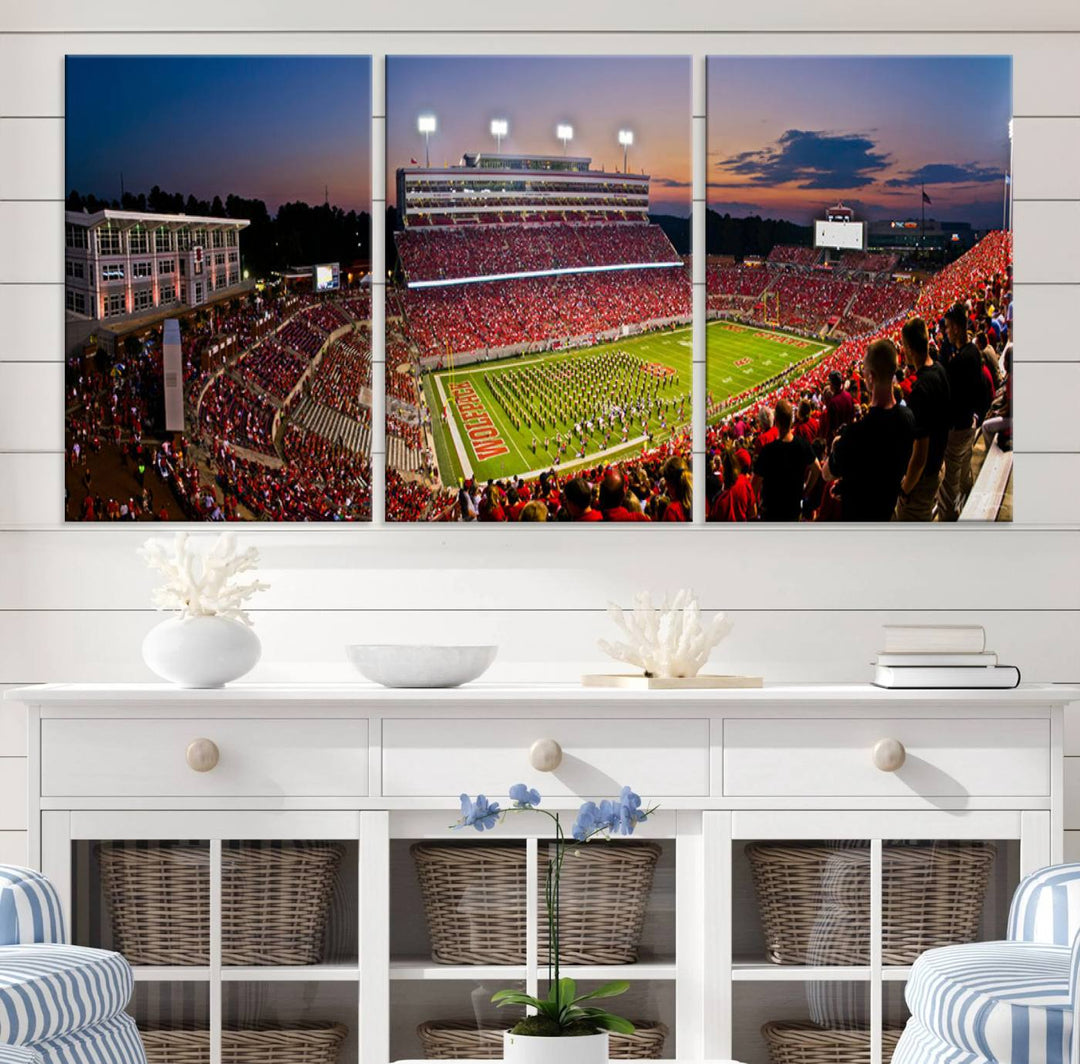 A print of a bustling Carter-Finley Stadium at dusk, featuring fans and a band, captures the essence of NC State Wolfpack football.