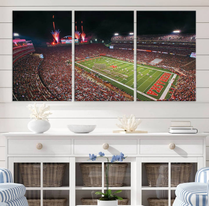 The University of Nebraska Cornhuskers Football Team Print, featuring Lincoln Memorial Stadium in a vibrant triptych canvas with fireworks above and a gallery-quality finish, is elegantly displayed.