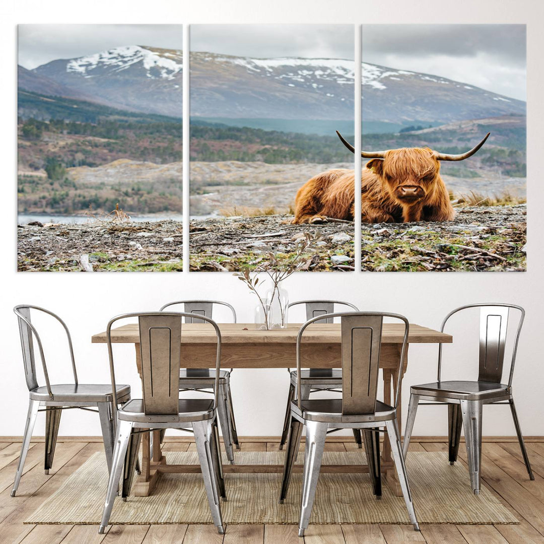 Highland Cow Horn Farm Wall Art Canvas Print is displayed against a wooden wall featuring a mountainous backdrop.