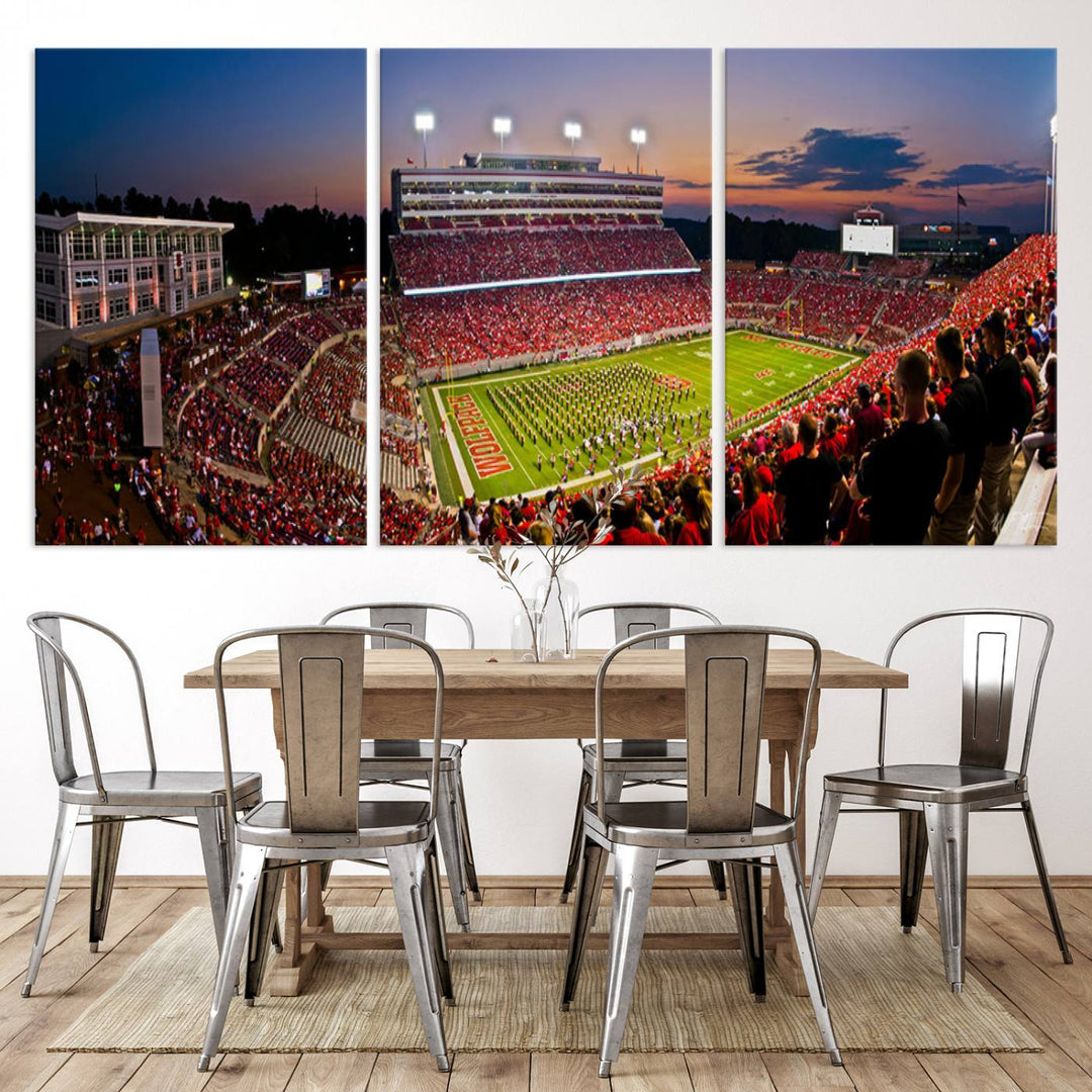 A print of a bustling Carter-Finley Stadium at dusk, featuring fans and a band, captures the essence of NC State Wolfpack football.