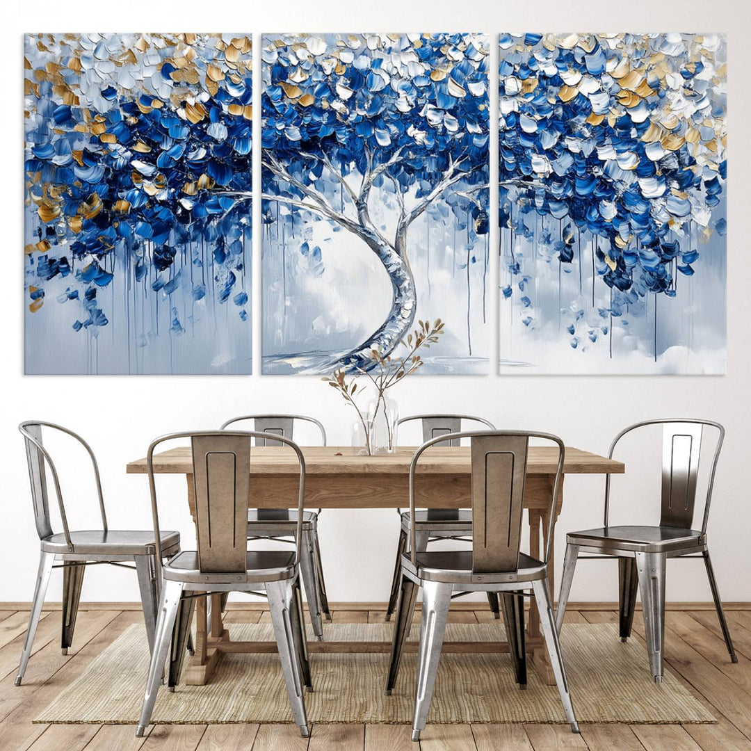 The Blue and Gold Abstract Tree Wall Art showcases a swirl trunk and features blue, silver, and gold leaves on a framed canvas print.