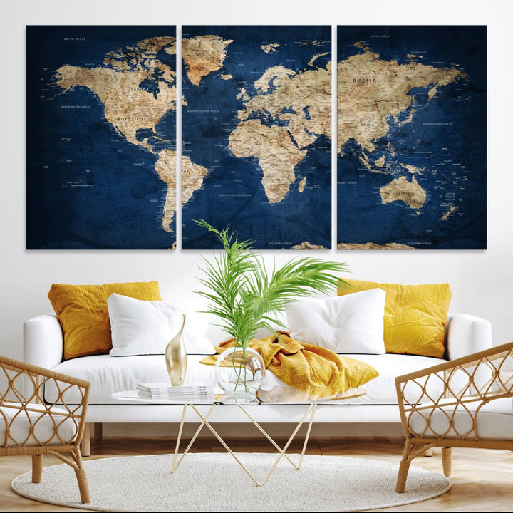 A large framed world map canvas print features beige landmasses set against a grunge-stained deep blue ocean background, creating an intriguing piece of wall art.