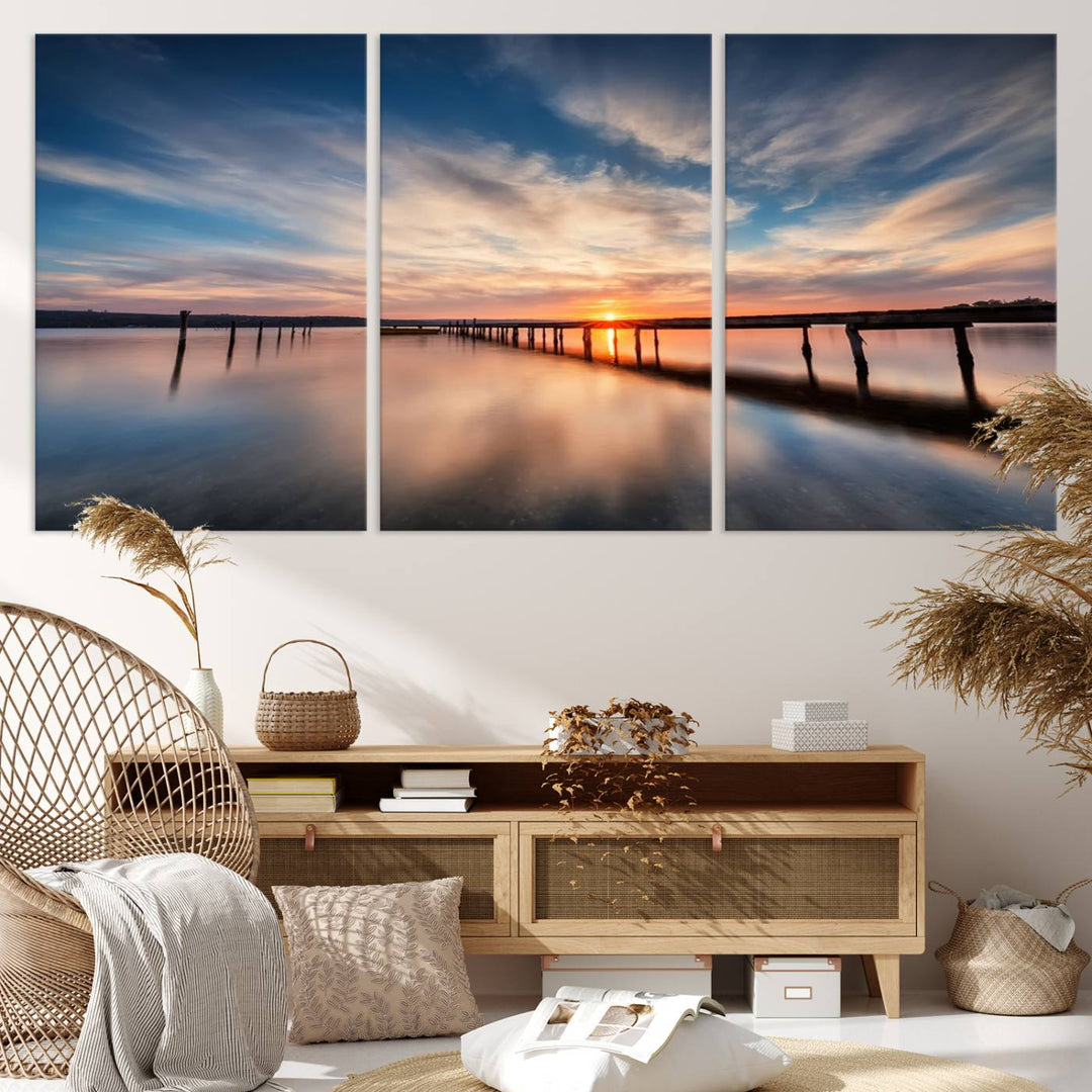 The tranquil sunset casting its glow over a peaceful lake with a long wooden pier captures the essence of coastal allure. The soft clouds mirrored in the water beautifully evoke the ambiance provided by the Sunset Pier Giclee Canvas Wall Art, a masterpiece designed for modern home decor and reminiscent of minimalist art.