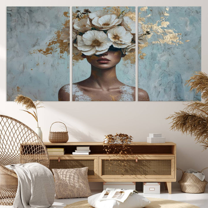 The Golden Petal Silhouette Woman Wall Art Canvas Print, a large 3-panel canvas with a textured gold floral design, serves as a luxurious centerpiece in modern glam settings. The artwork depicts a woman with flowers over her eyes against a textured background and hangs elegantly.