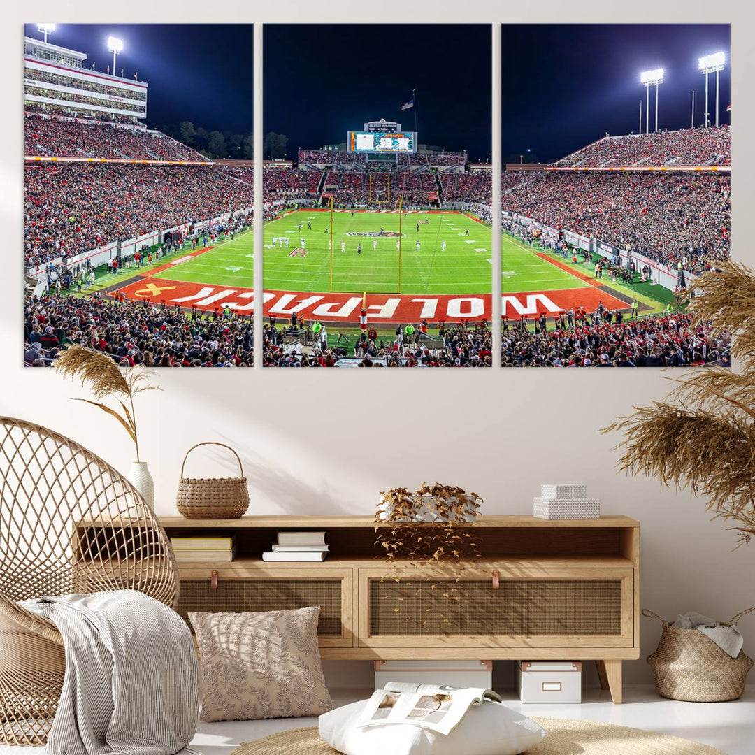 A NC State Wolfpack Football Team print of Carter-Finley Stadium at night features WOLFPACK illuminated brightly in the end zone grass.