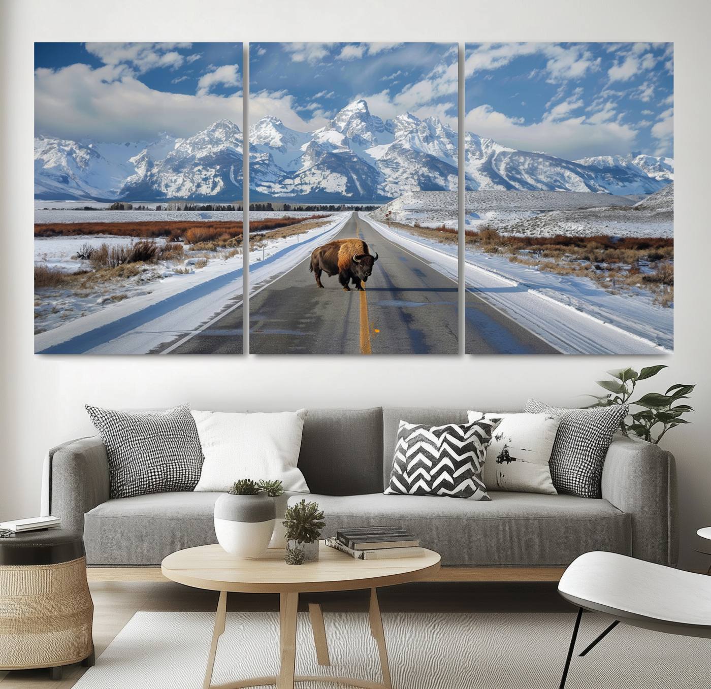 A powerful bison stands on a snow-dusted road beneath the towering peaks of the Grand Tetons, capturing the untamed beauty of America's winter wilderness.