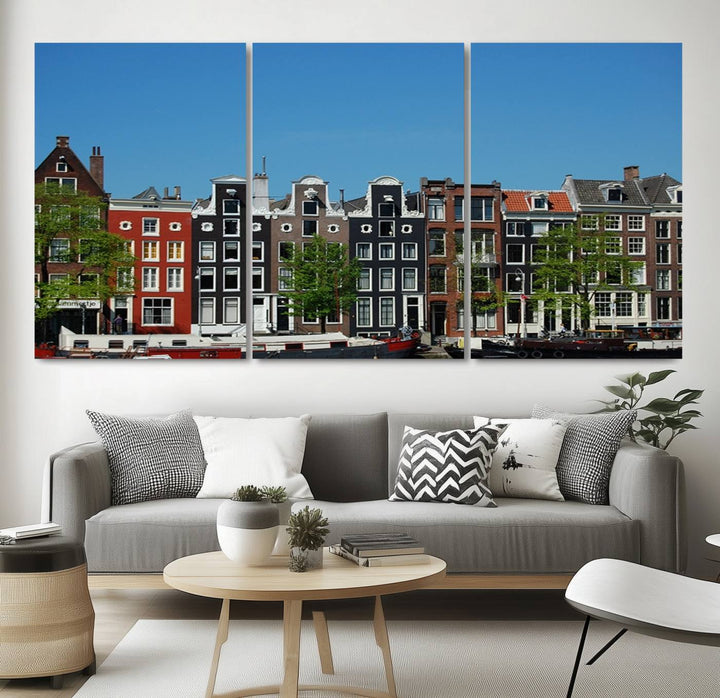 The Amsterdam City Wall Art Canvas Print showcases colorful traditional canal houses and boats set against a clear blue sky.