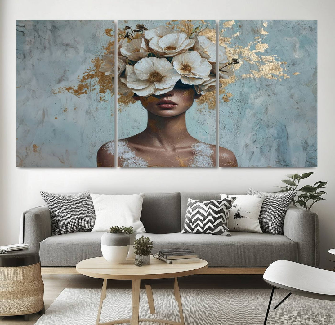 The Golden Petal Silhouette Woman Wall Art Canvas Print, a large 3-panel canvas with a textured gold floral design, serves as a luxurious centerpiece in modern glam settings. The artwork depicts a woman with flowers over her eyes against a textured background and hangs elegantly.