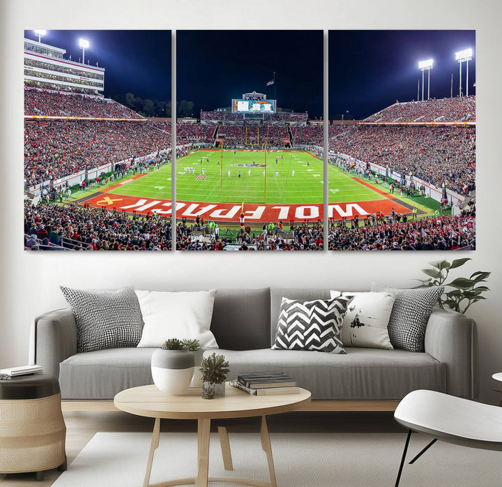 A NC State Wolfpack Football Team print of Carter-Finley Stadium at night features WOLFPACK illuminated brightly in the end zone grass.