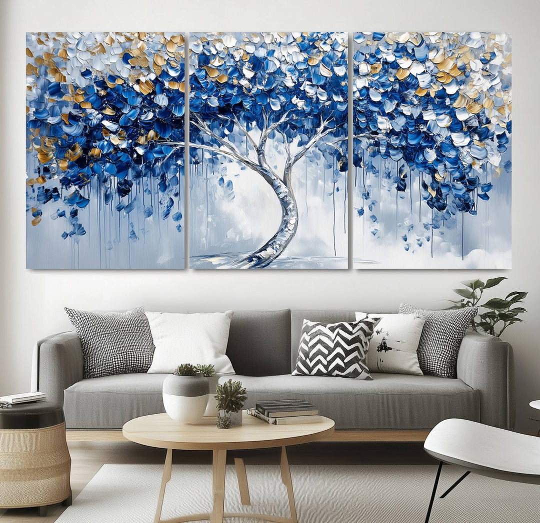 The Blue and Gold Abstract Tree Wall Art showcases a swirl trunk and features blue, silver, and gold leaves on a framed canvas print.