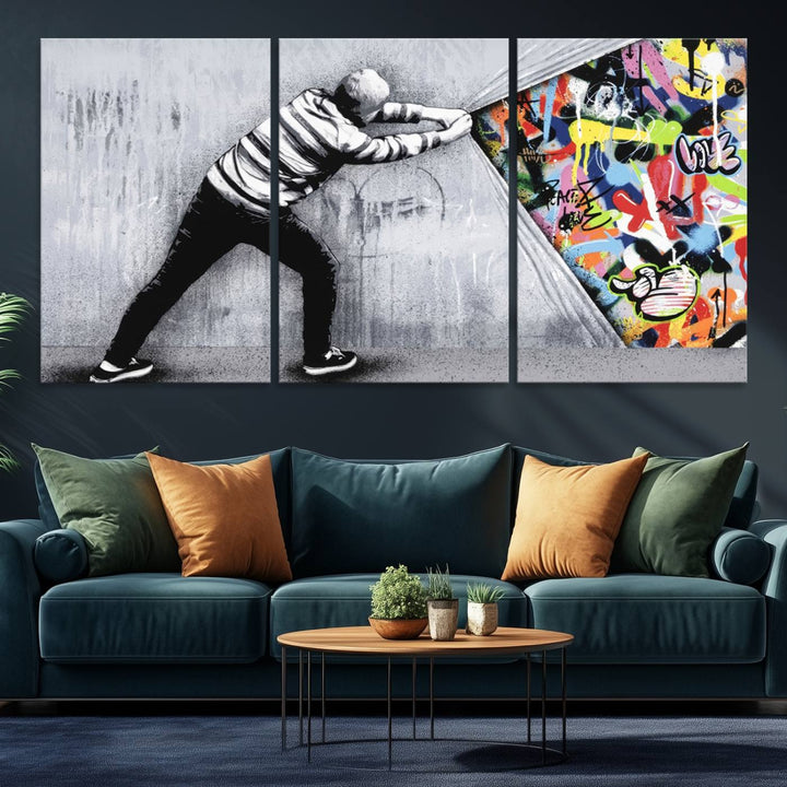 A 3-panel print of Banksys Art Behind the Curtain reveals colorful graffiti beneath a peeling wall.