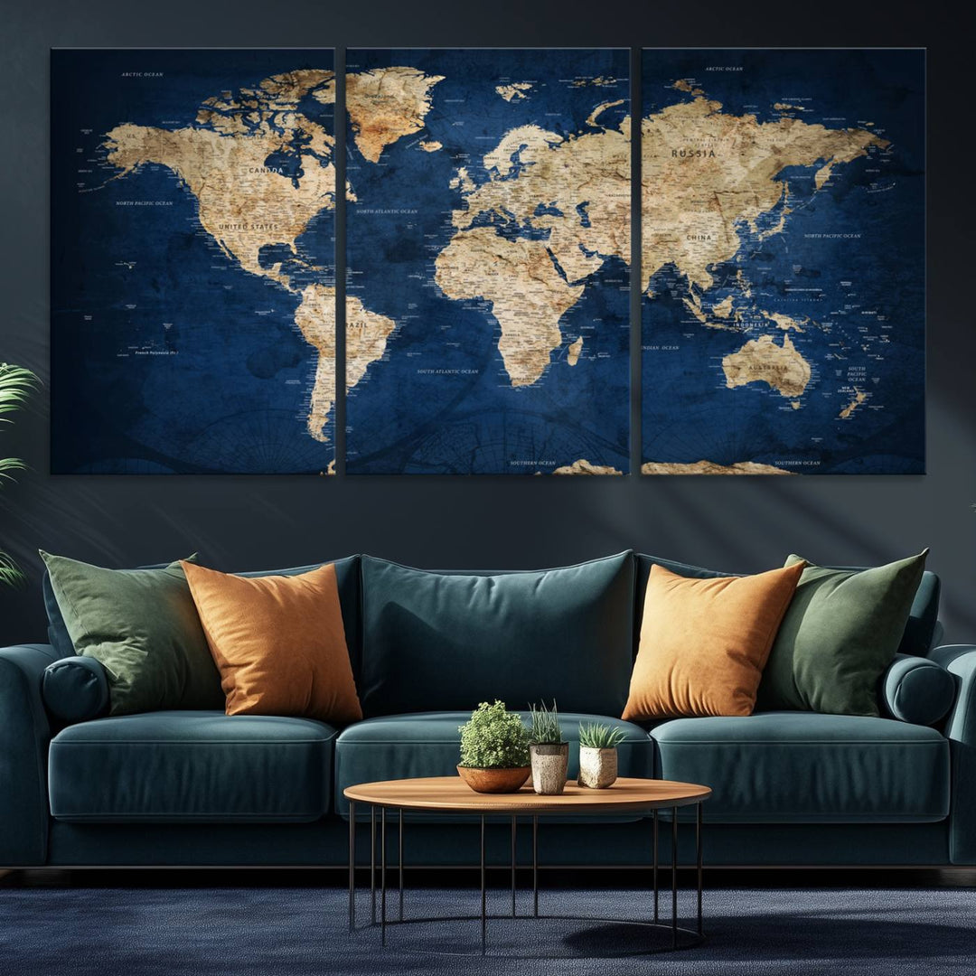 A large framed world map canvas print features beige landmasses set against a grunge-stained deep blue ocean background, creating an intriguing piece of wall art.